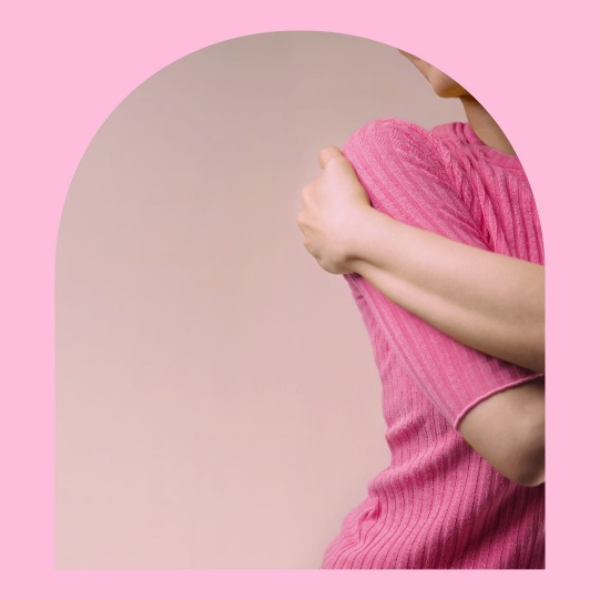 Femme en haut rose se prenant dans les bras, symbole de bienveillance et d’amour de soi après un cancer du sein.